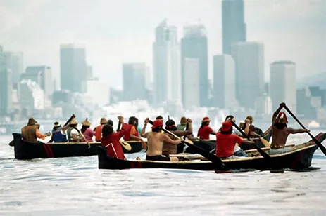 people in canoes with city skyline in distance