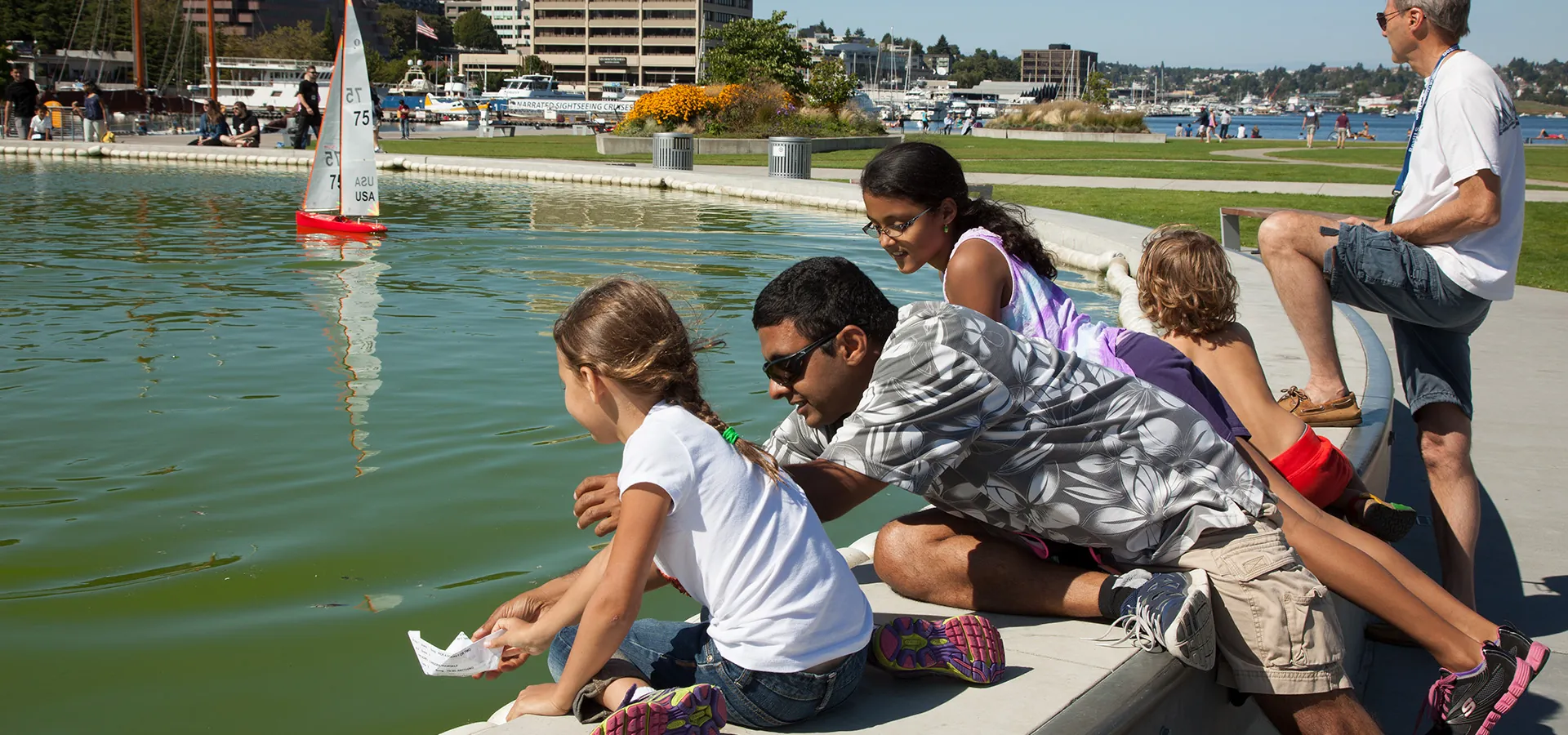 adults and children playing with toy boats