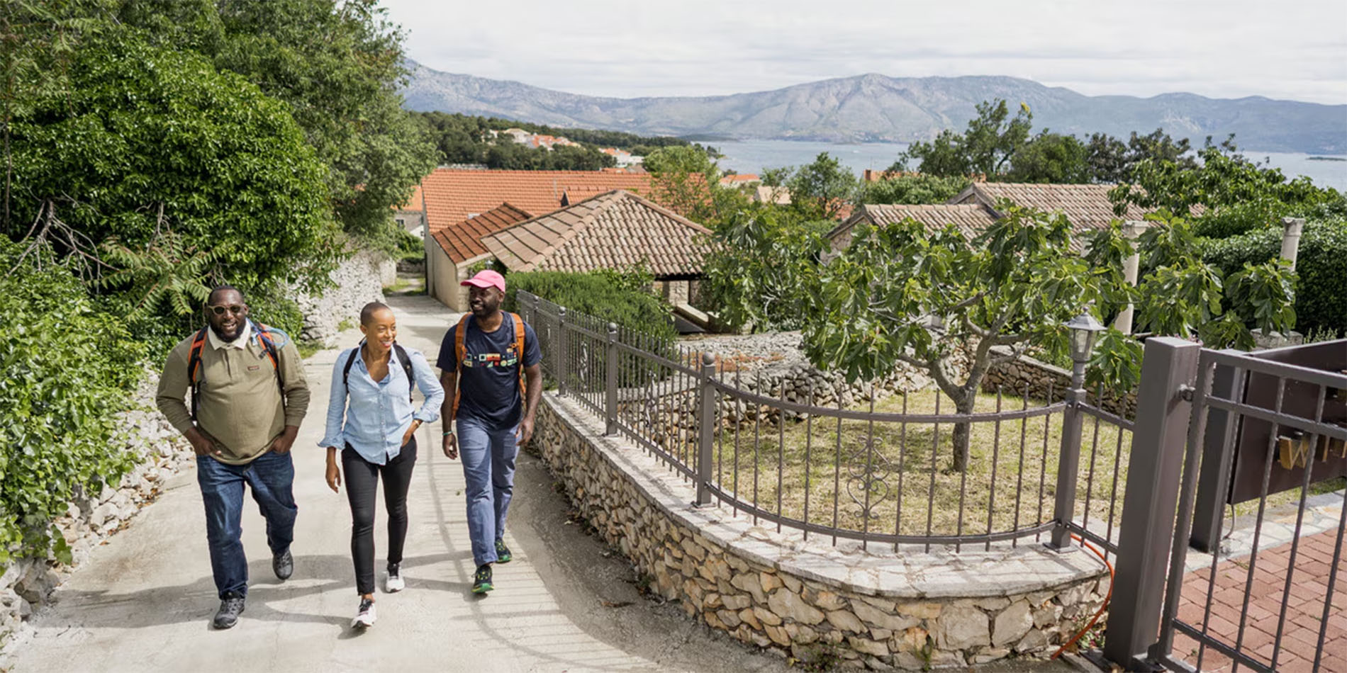 three people walking up hill with mountain in background