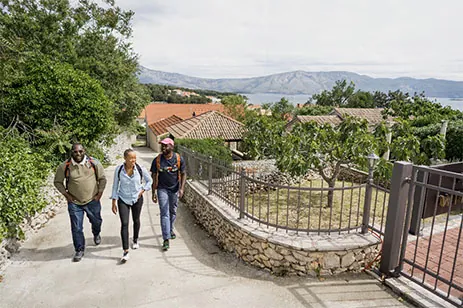 three people walking up hill with mountain in background