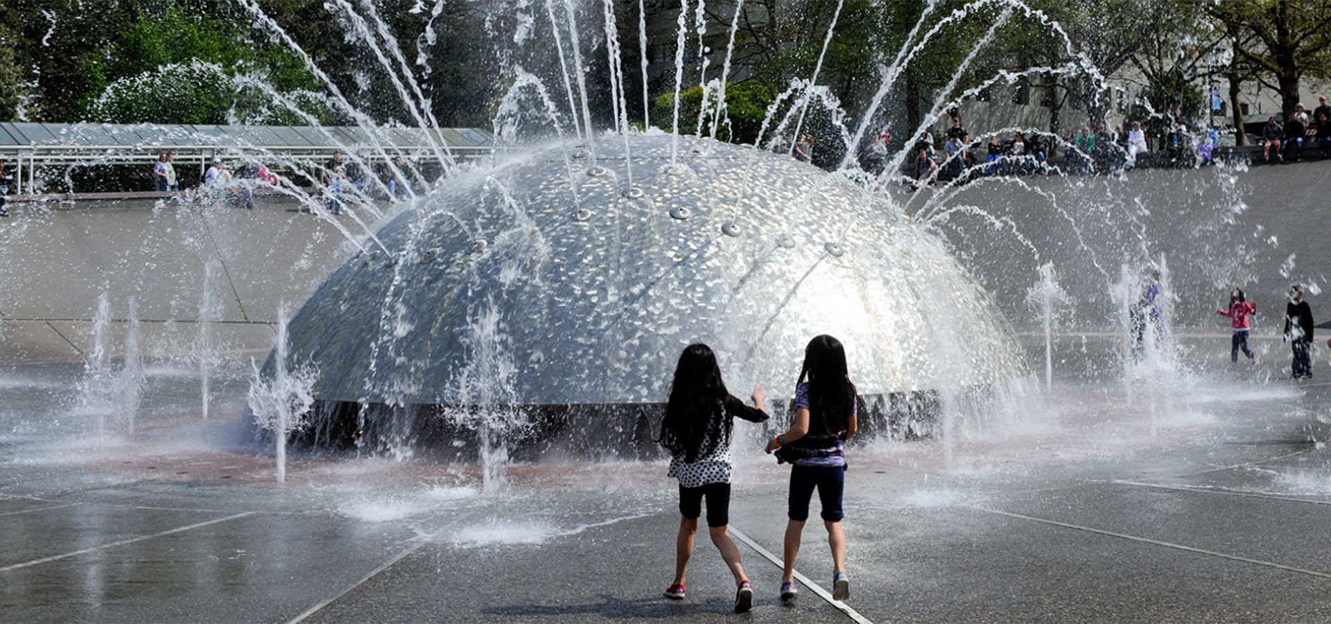 two girls playing in front of fountain